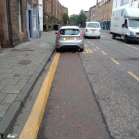 A photo of a bike lane with a car in it